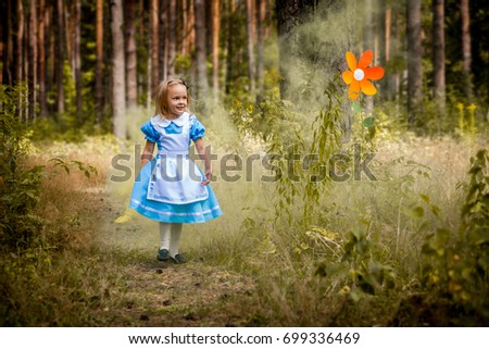 "Alice in Wonderland" styled photoshoot in forest. Girl in light blue dress walk in forest. Royalty-Free Stock Photo #699336469