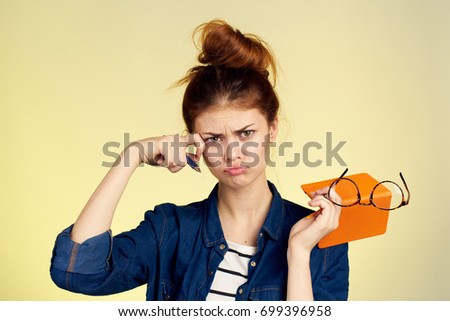 Accountant sad woman holding a notebook and glasses on a yellow background in her hand                               