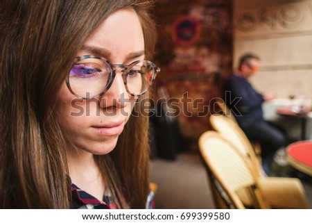 Beautiful stylish girl wearing glasses sitting in cafe in Paris