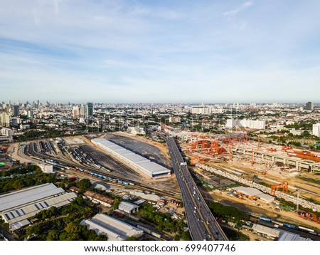 The very high aspect of new Bangkok main train station with cars traveling beside on highway. While train station is constructing on right side of highway, old trains are also parking on another side.