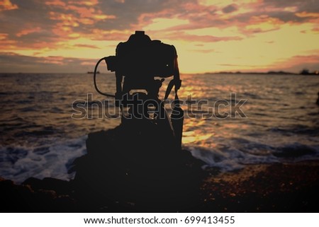 Silhouette camera dslr is taking a picture of the sea background sunset.