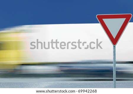 Give way yield road traffic sign and motion blurred truck in the background