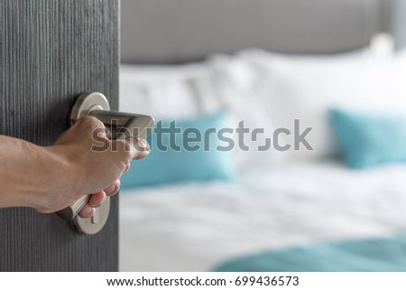 Hand hold doorknob opening to hotel bedroom