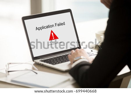 Application failed, businessman having problem with laptop, bad software failure on screen, broken computer stopped working in office, hanging pc caused system crash error message, close up rear view Royalty-Free Stock Photo #699440668