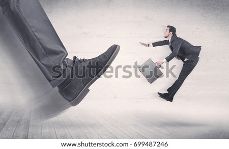 Big foot in a black shoe fire small, young, businessman who is flying away in the space
