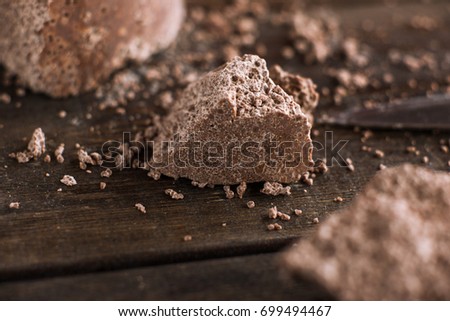Broken off pieces of aerated chocolate on wooden table. Process of making delicious desserts in restaurant, culinary art close up picture