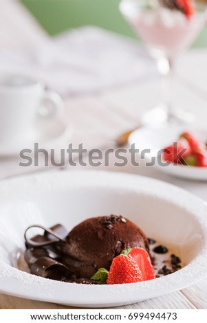 Chocolate fondant on white plate with decoration from strawberry and mint. 