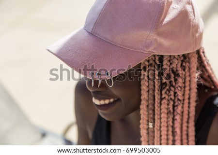 African young girl in a black bathing suit and cap with long pink pigtails posing in the background of the beach and ocean