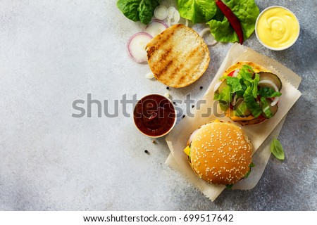 A delicious fresh homemade hamburger on a slate or stone table. Cheeseburger with meatball and vegetables. Street food, fast food. Top view with copy space. Royalty-Free Stock Photo #699517642