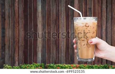 woman hand holding the glass iced coffee on wooden background,Iced latte coffee