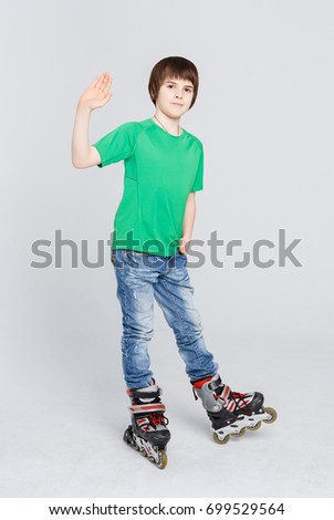 Happy boy in roller skates waving his hand at studio white background. Ready to have fun. Active and safety lifestyle concept, vertical, copy space