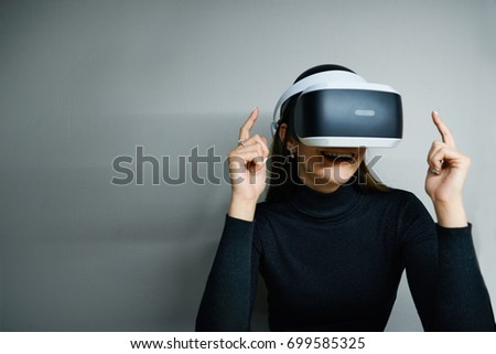 Picture of fascinated excited young brunette female wearing virtual reality modern glasses with head mounted display, entertaining herself, playing video games or watching something amazing