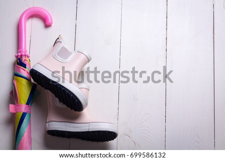 Pink little children rubber boots with colorful umbrella, concept of autumn or spring background.