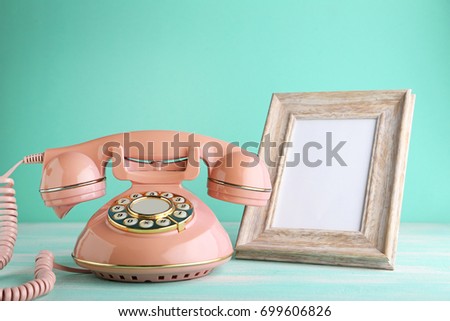 Pink retro telephone with photo frame on wooden table