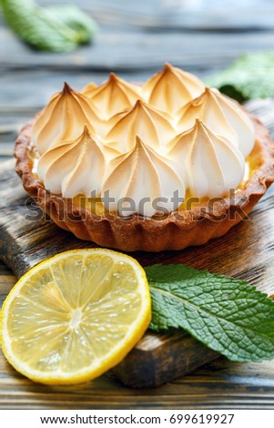 Tartlet with lemon cream and meringue on wooden stand, selective focus.