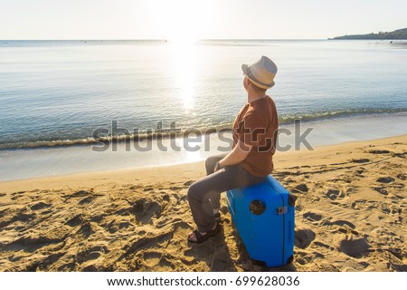 Man with suitcase on the beach. Summer travel and vacation concept