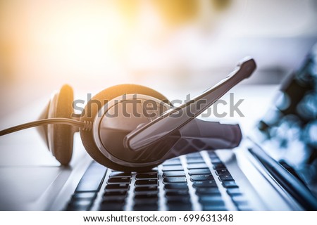 Communication support, call center and customer service help desk. VOIP headset on laptop computer keyboard. Royalty-Free Stock Photo #699631348
