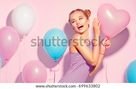 Beauty girl with colorful air balloons laughing over pink background. Beautiful Happy Young woman on birthday holiday party. Joyful model having fun, playing and celebrating with pastel color balloon