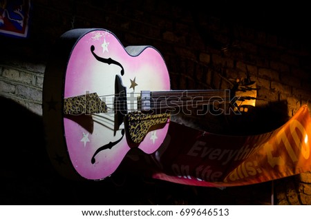 pink guitar in a dark shop