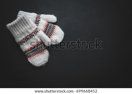Christmas decorations. White knitted mittens with a winter pattern of snowflakes on a black background