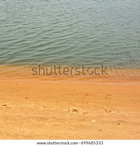 Sand beach background. Top view. Backdrop of yellow sand and rippled water. Travel & Vacation concept. Textured structure. Nice ocean coast. Wonderful landscape. 