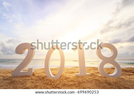 New year concept : Close up white wooden alphabet 2018 setup on the sunset beach. Warm tone color with lens flare. 