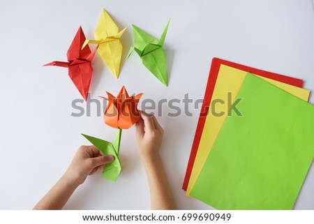 Children's hands do origami from colored paper on white background. lesson of origami Royalty-Free Stock Photo #699690949