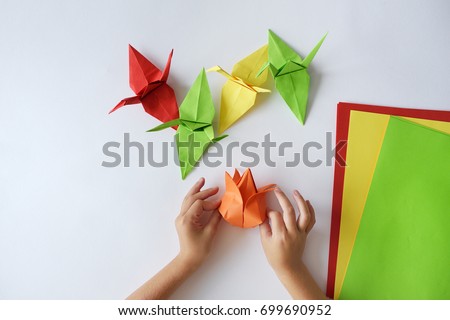 Children's hands do origami from colored paper on white background. lesson of origami Royalty-Free Stock Photo #699690952