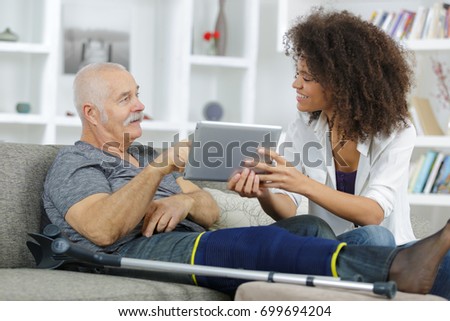 old man using tablet with the help of an assitant