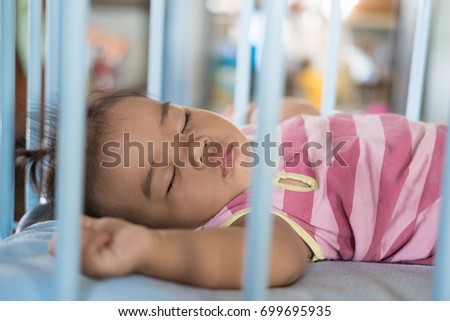 Baby girl is sleeping in baby cot. Royalty-Free Stock Photo #699695935