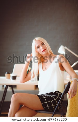Fashion designers working in studio sitting on the desk.