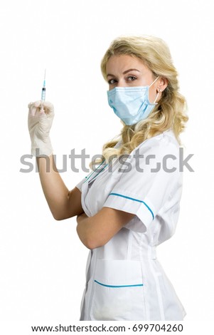 Beautiful blond nurse with syringe. Female young doctor or nurse wearing a surgical mask holding up her hand with a syringe over white background, side view.