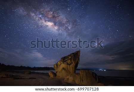 Milkyway rise above a standing stone by the beach. Image contain soft focus and blur due to long expose. Image also contain noise and grains due to high ISO.