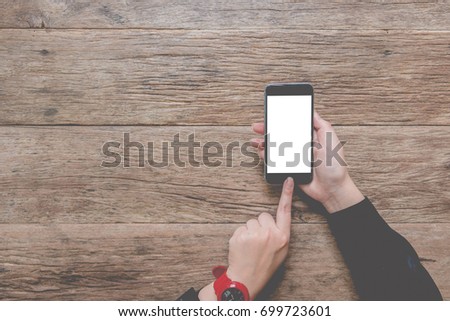 Girl hand using smartphone with blank screen mobile on wooden desk. top view. Graphic display montage.