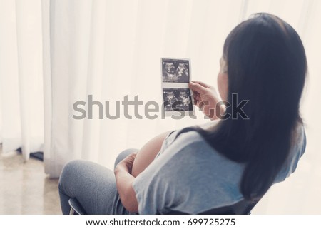 Pregnant woman holding ultrasound scan film,,Family love, pregnancy and motherhood concept 