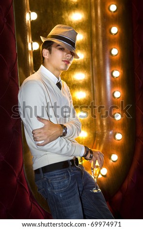 young man with glass of champagne near the mirror in cabaret