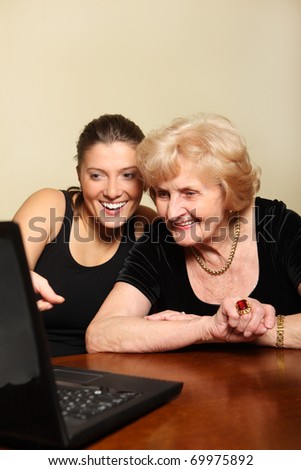 A picture of a granddaughter showing something on the laptop to her grandma