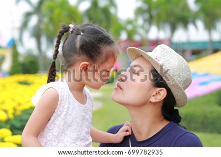 Mother and child girl kissing in the public park. Abstract Happy loving family.