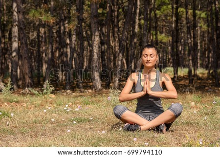 Beautiful girl practicing yoga in the morning forest