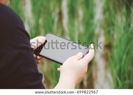 people holding smartphone with nature background. subject is blurred.