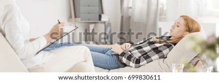 Young patient during hypnosis seance at psychotherapist's office Royalty-Free Stock Photo #699830611