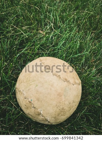 Close up old softball on green grass background in daylight / With Copy Space