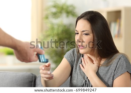 Asthmatic girl suffering an asthma attack receiving an inhaler at home Royalty-Free Stock Photo #699849247