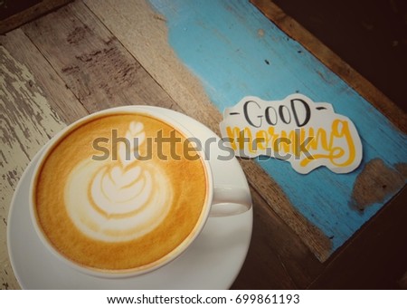 Good morning coffee concept. hot coffee in white cup with latte art and calligraphy greeting words on vintage wood background