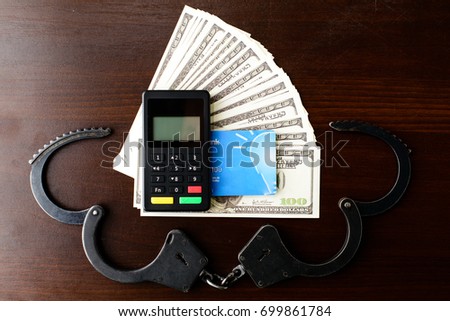 steel police handcuffs, dollars money, payment device and bank card on wooden background, top view. Concept of illegal payment, bribery, venality, corruption and fraud
