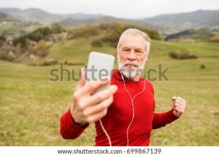Active senior runner in nature taking selfie with smart phone.