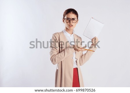 The teacher in glasses holds a notebook and pencil on a light background teaches at school                               