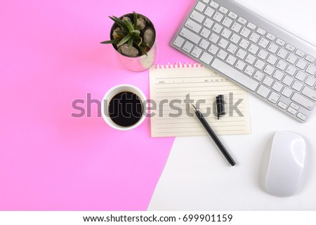 Office table with keyboard, mouse, notebook and smartphone on modern two tone (white and pink) background.