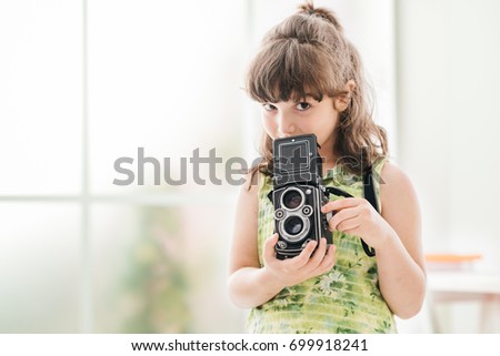 Cute photographer girl holding a vintage twin-lens reflex camera