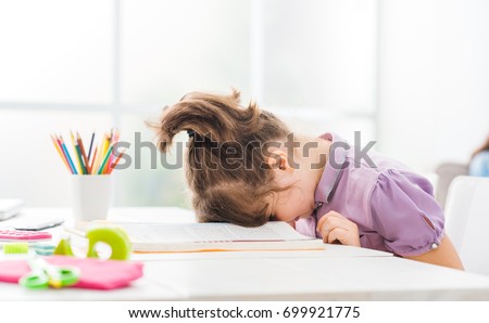 Lazy student girl at home, she is resting with her face down on the school book, education and childhood concept